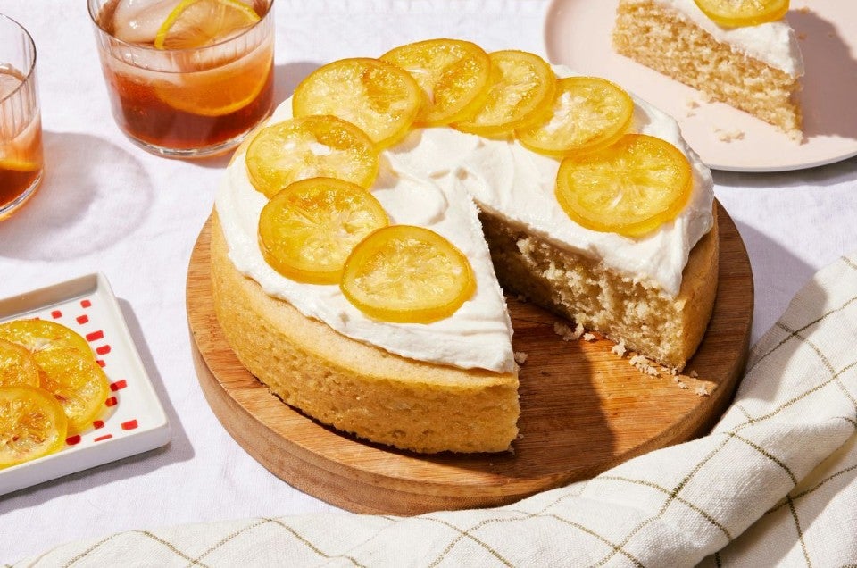 A simple, single layer lemon cake topped with frosting and candied lemon slices